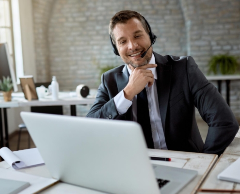 Image of a business person using a computer and a headset.