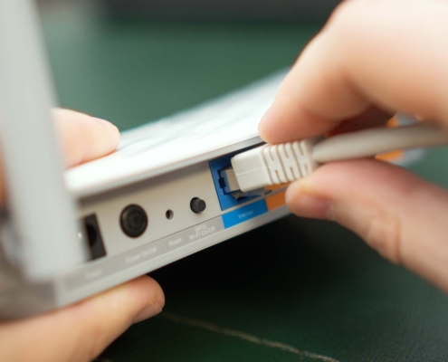 Low Voltage Cabling image person plugging in cable to router