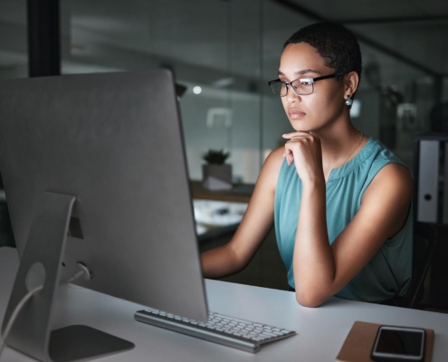 Side view of a professional woman looking at a computer screen in a dimly lit room