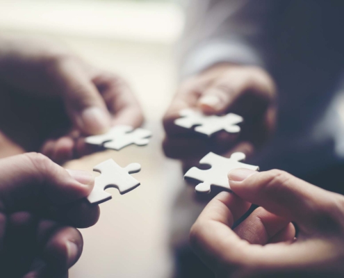 View of four people putting puzzle pieces together